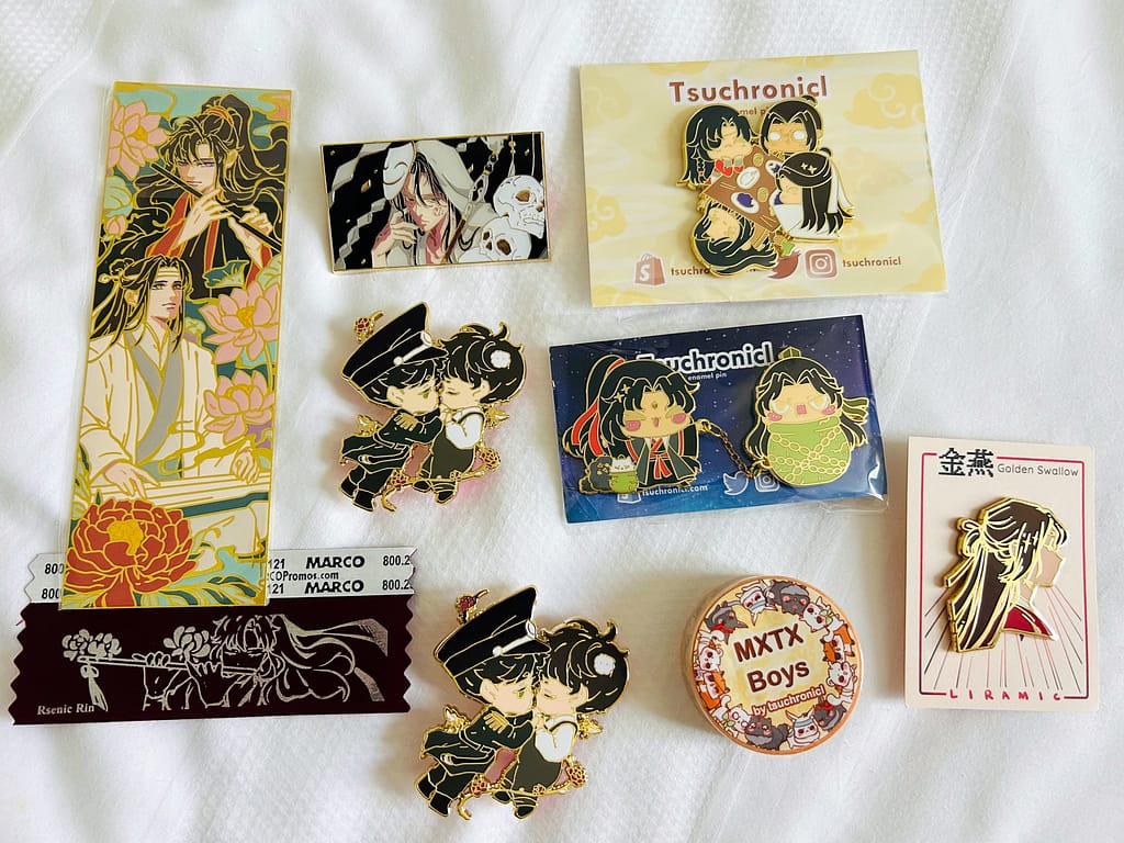Pins and merch from day one of Otakon, including works by Rsenic Rin, tsuchronicl, and Liramic.